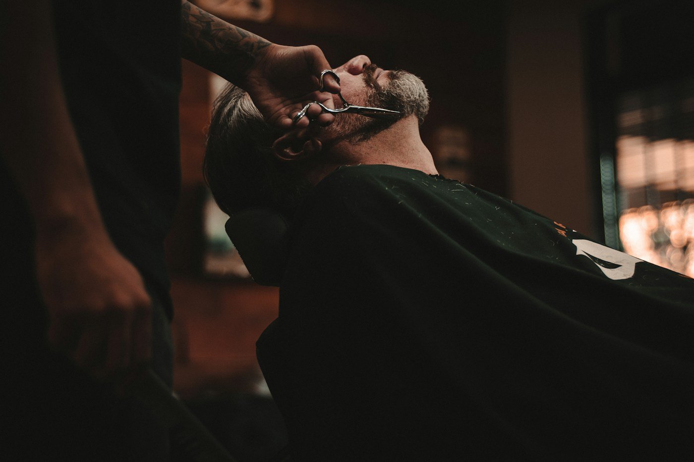 Barber carefully shaping a client’s beard with scissors